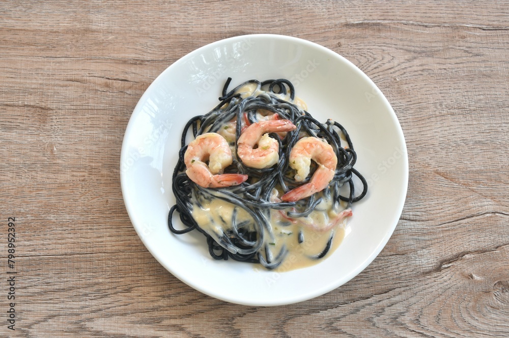 black squid ink spaghetti with shrimp dressing white carbonara cream sauce on plate 