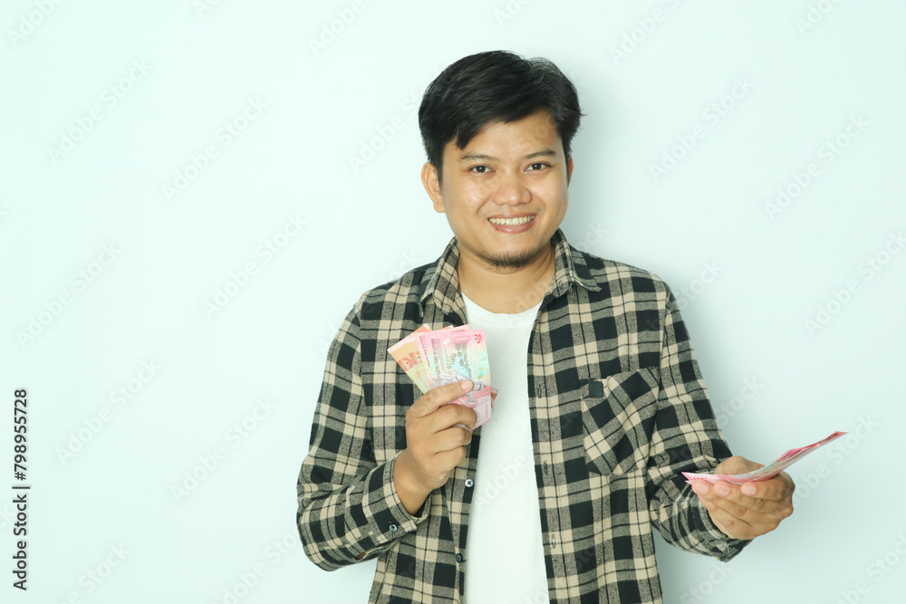 Young Asian man wearing brown flannel shirt smiling happy while giving money to someone Young Asian man wearing brown flannel shirt smiling happy while giving money to someone