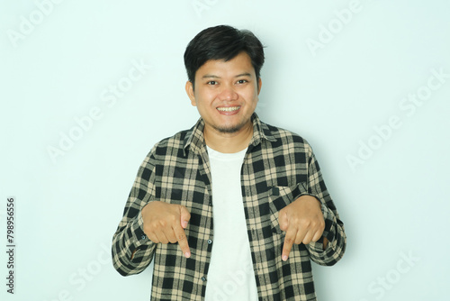 Young Asian man smiling happy while pointing down photo