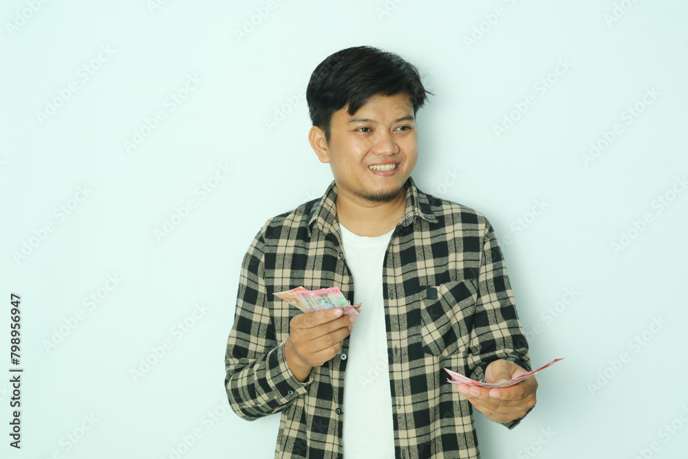 Young Asian man wearing brown flannel shirt smiling happy while giving money to someone Young Asian man wearing brown flannel shirt smiling happy while giving money to someone