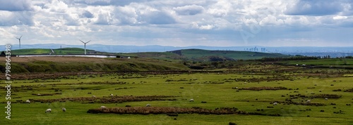 Panoramic image of a countryside area of Manchester showing green field with live stock and wind turbines.  photo