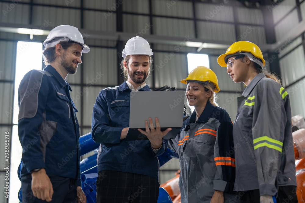 A diverse group of smiling industrial professionals collaborates over a laptop on the factory floor, embodying teamwork and technological integration in manufacturing. A diverse group of smiling industrial professionals collaborates over a laptop on the factory floor, embodying teamwork and technological integration in manufacturing.