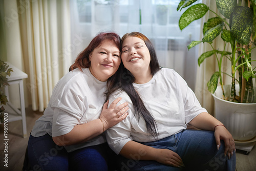 Happy Overweight family with mother and daughter in room. Middle aged woman and teenager girl having fun, joy, hugging
