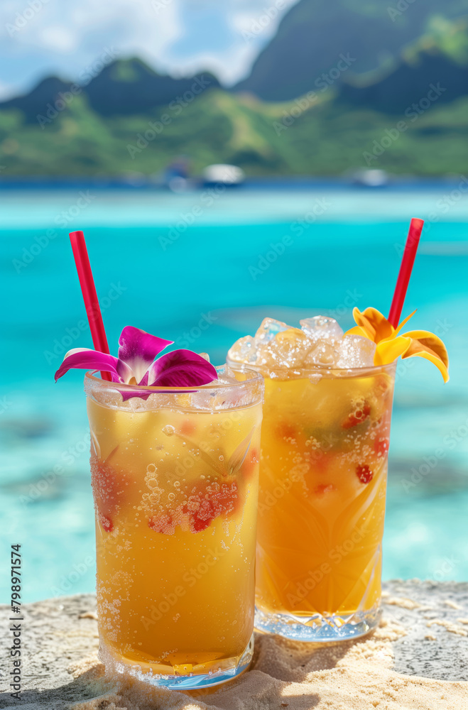 Obraz premium Exotic cocktails with tropical fruits in glasses with tropical coastline as a backdrop.