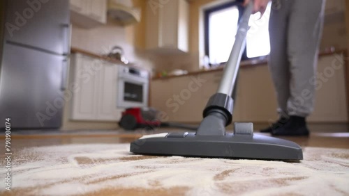 The vacuum cleaner brush collects cereal scattered in the kitchen. Close-up, slow motion
