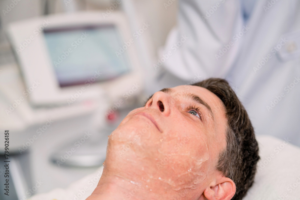 caucasian man waiting surgeon checking machine on bed. handsome patient laying on bed while medical staff trying to start therapy engine. white man lying on bed waiting for doctor checking machine