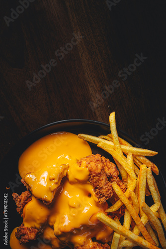 top view of crispy chicken bits with cheddar sauce and french fries