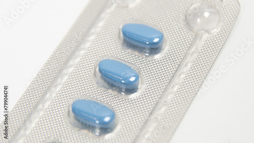 Blue pills for treating erectile dysfunction or impotence, in foil on a white table. Close up.