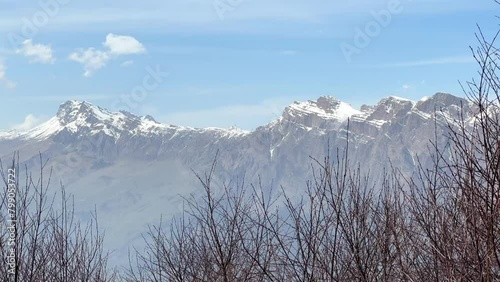 Archonsky Pass. The pass connects the Kurtatinsky gorge with the Alagirsky. Alanya, view of the mountains of the North Caucasus, peaks covered with snow. Sunny day, blue sky with a slight haze. 4К photo