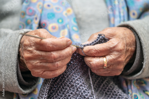 Close up of a mature woman knitting at home  enjoying leisure time  holding needles  elderly generation hobby activity. High quality photo
