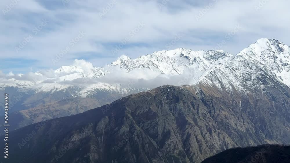 Archonsky Pass. The pass connects the Kurtatinsky gorge with the Alagirsky. Alanya, view of the mountains of the North Caucasus, peaks covered with snow. Sunny day, blue sky with a slight haze. 4К Archonsky Pass. The pass connects the Kurtatinsky gorge with the Alagirsky. Alanya, view of the mountains of the North Caucasus, peaks covered with snow. Sunny day, blue sky with a slight haze. 4К