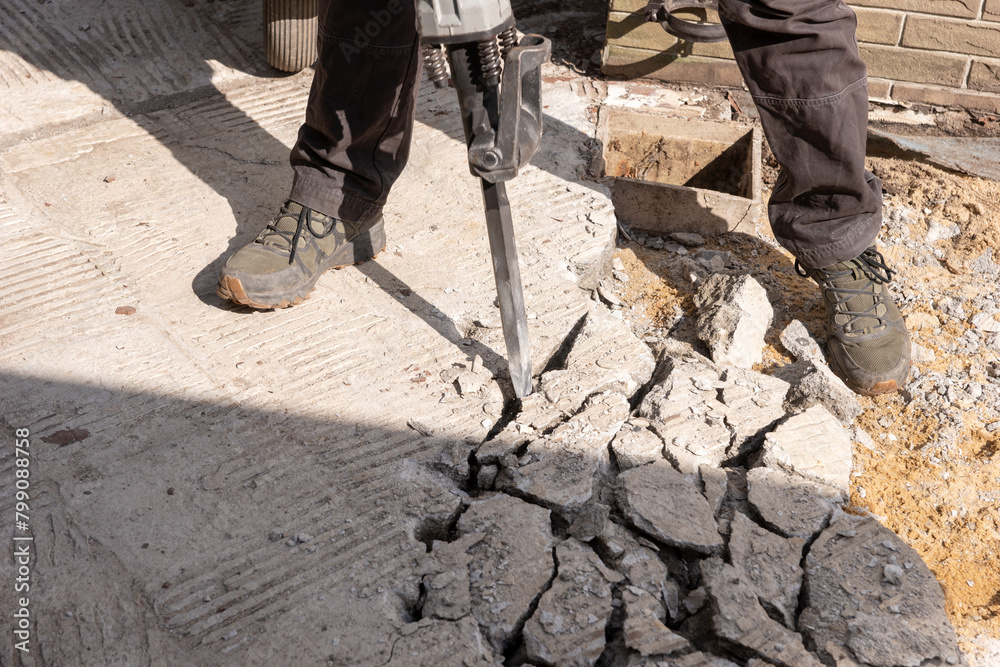 Construction worker chisels the concrete slab with a hammer drill Construction worker chisels the concrete slab with a hammer drill