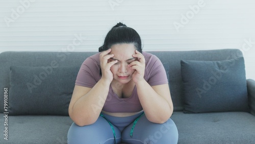 chuuby woman sitting on sofa using tape to measure her waist circumference