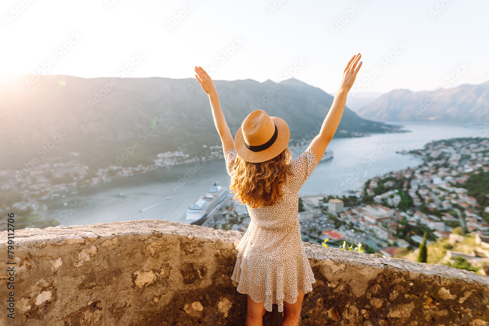 Young woman is looking at landscape of city from height. Travel in Europe. Back view.