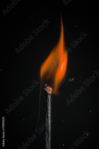 burning wooden match on a black background. Match head with burning gray at the end, flame, copy space. Creative banner of energy, fuel industry.