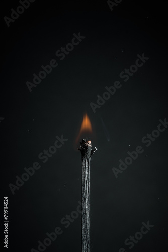 burning black match on a black background, space for text. fire small flame