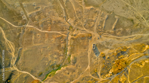 Traces of dirt roads and ruined houses mark the site of a former village, now submerged beneath the reservoir formed by a breached dam, with only the surviving church of St. Ivan Rilski, Bulgaria