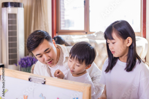 In the living room, the young father accompanied the two siblings to play games © 大 李