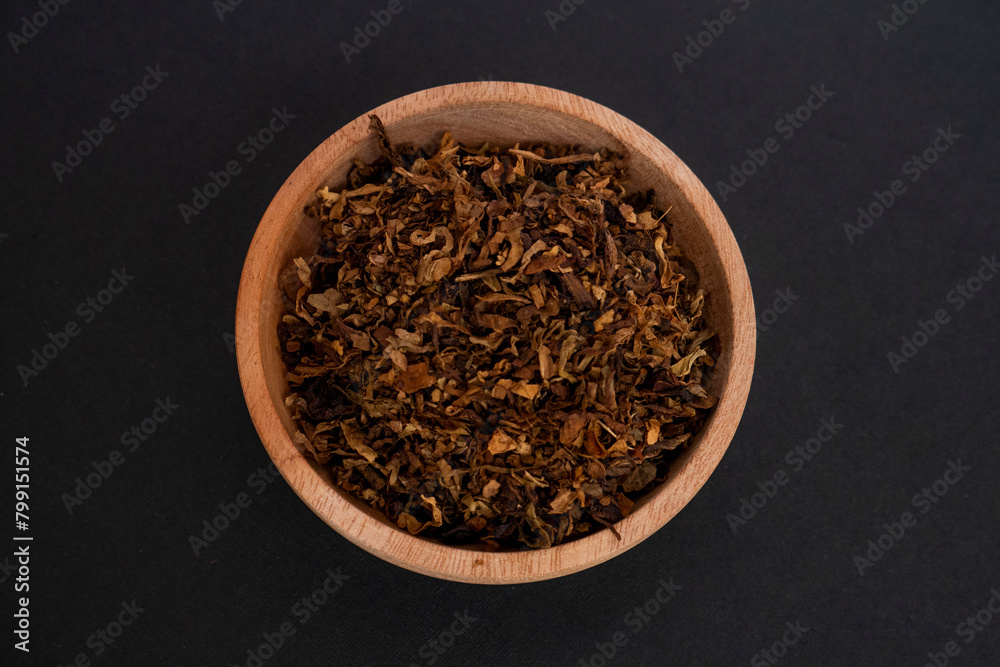 tobacco leaf granules on a wooden bowl with black isolated object. flatlay view. tobacco leaf granules on a wooden bowl with black isolated object. flatlay view.
