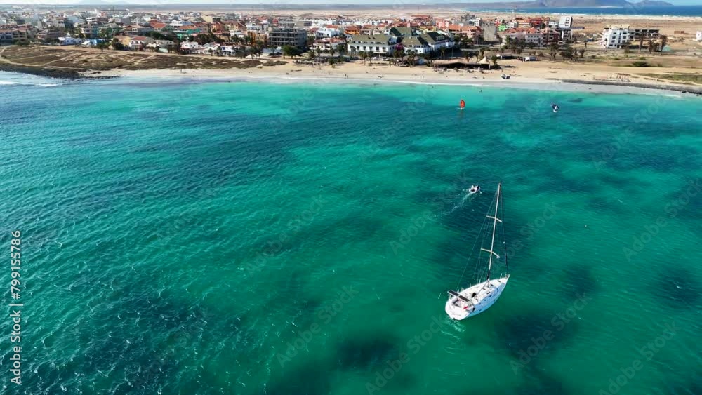 View from above of the sea and the beach of Santa Maria, Sal, Cape Verde, orbit around a yacht. The beach and a wing foiler in the background
