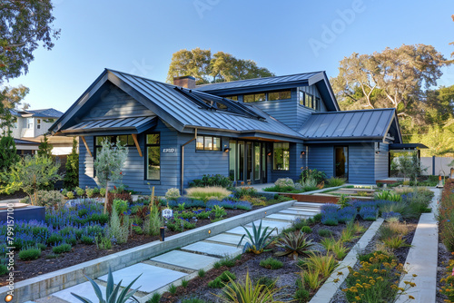 A modern electric blue craftsman cottage style home, featuring a triple pitched roof, with artistic landscaping and a smoothly integrated walkway, highlighting innovative design.