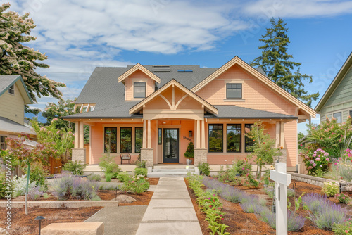 A newly constructed soft peach craftsman cottage style home, showcasing a triple pitched roof, thoughtful landscaping, 
