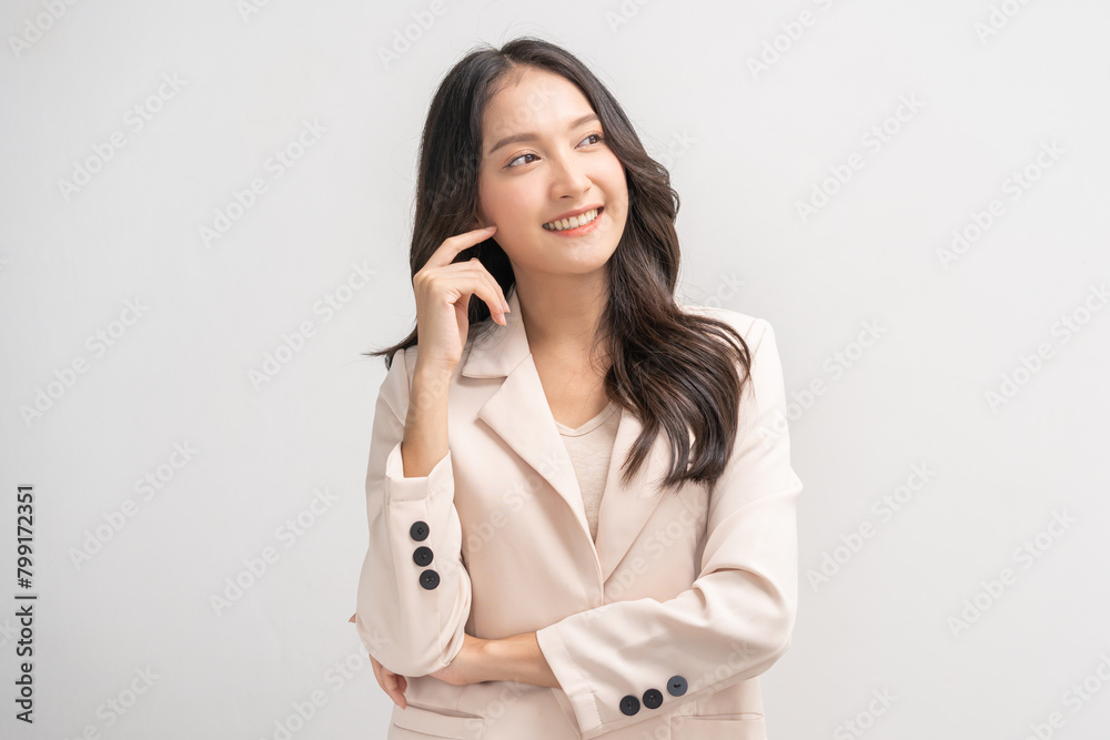 Smiling positive, attractive asian young woman in beige suit formal dress, pointing finger away. Portrait pretty girl with long brunette hair, feeling happy isolated on white background, copy space. Smiling positive, attractive asian young woman in beige suit formal dress, pointing finger away. Portrait pretty girl with long brunette hair, feeling happy isolated on white background, copy space.