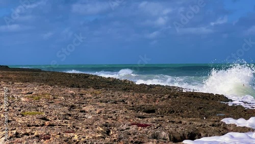 Rocky Cuban beach in Varadero, Cuba, on a cloudy day, when the sun breaks through the clouds, you can see the waves and ocean expanses. Turquoise waves. Stone slabs on the beach in the ocean. 4K	 photo