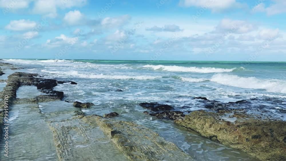 Rocky Cuban beach in Varadero, Cuba, on a cloudy day, when the sun breaks through the clouds, you can see the waves and ocean expanses. Turquoise waves. Stone slabs on the beach in the ocean. 4K Rocky Cuban beach in Varadero, Cuba, on a cloudy day, when the sun breaks through the clouds, you can see the waves and ocean expanses. Turquoise waves. Stone slabs on the beach in the ocean. 4K