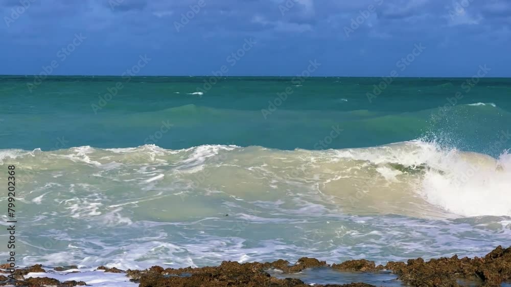 Rocky Cuban beach in Varadero, Cuba, on a cloudy day, when the sun breaks through the clouds, you can see the waves and ocean expanses. Turquoise waves. Stone slabs on the beach in the ocean. 4K Rocky Cuban beach in Varadero, Cuba, on a cloudy day, when the sun breaks through the clouds, you can see the waves and ocean expanses. Turquoise waves. Stone slabs on the beach in the ocean. 4K