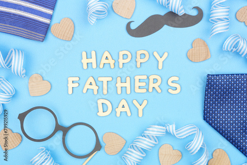 Happy Fathers Day message with frame of gifts, decor, ties and ribbon on a blue background. Top view.