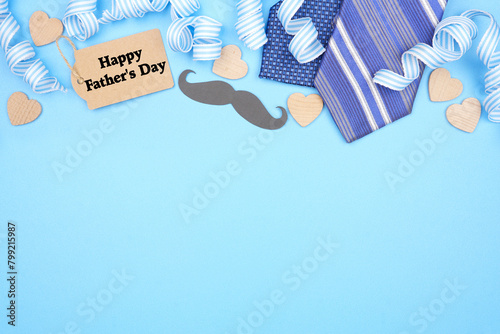 Happy Fathers Day gift tag with top border of gifts, decor, ties and ribbon. Overhead view on a blue background. Copy space.