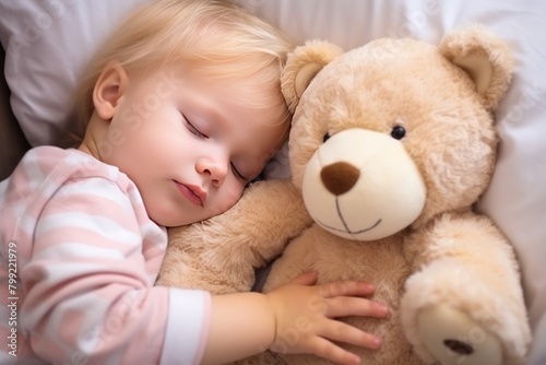 Toddler boy with dark hair in shirt sleeps sweetly in company of best friend teddy bear seeing pleasant dreams. Little Caucasian boy has sweet dreams in bed with favorite toy small teddy bear
