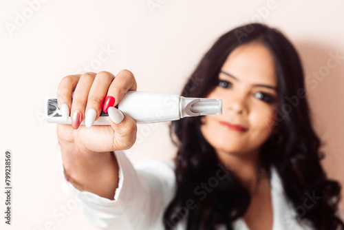 Young Hispanic Woman Holding a Laser For Skin Care.
