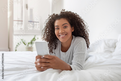 Woman Laying on Bed Holding Cell Phone