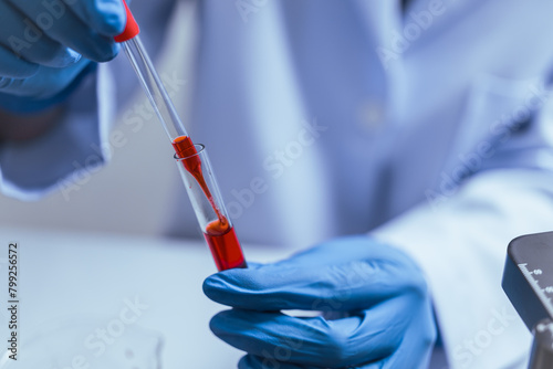 Hands of a doctor or female doctor collecting blood sample tubes from rack with analyzer in lab. Doctor holding blood test tube in research laboratory red blood cells