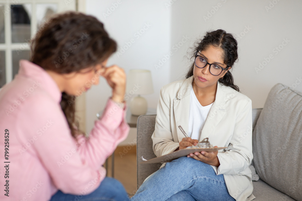 Women Therapist and Client Sitting on Couch Talking Women Therapist and Client Sitting on Couch Talking