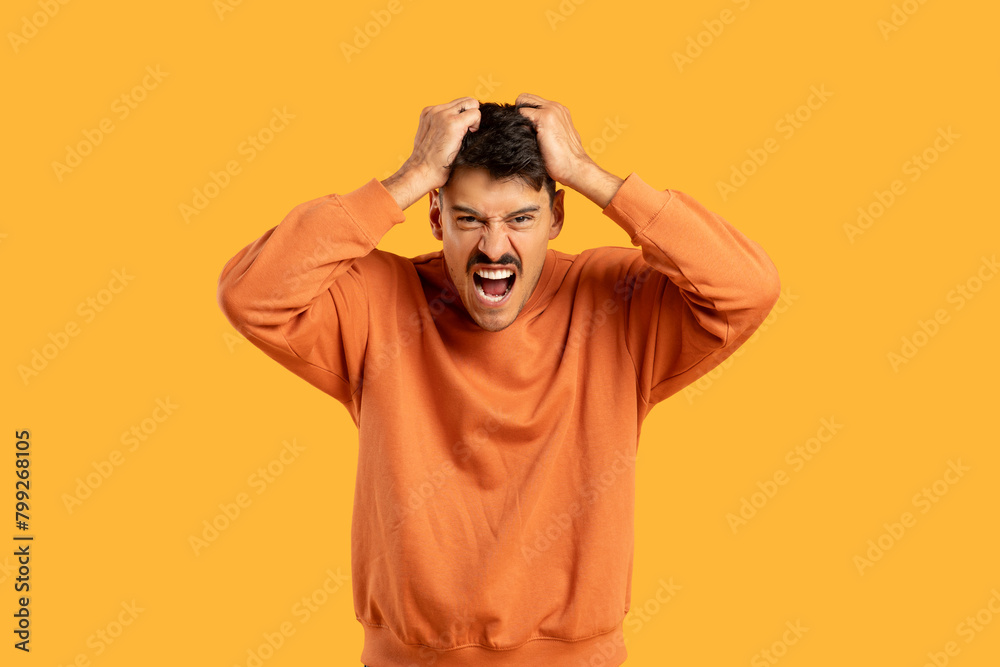 Man in Orange Shirt Holding Hair in Anger Man in Orange Shirt Holding Hair in Anger