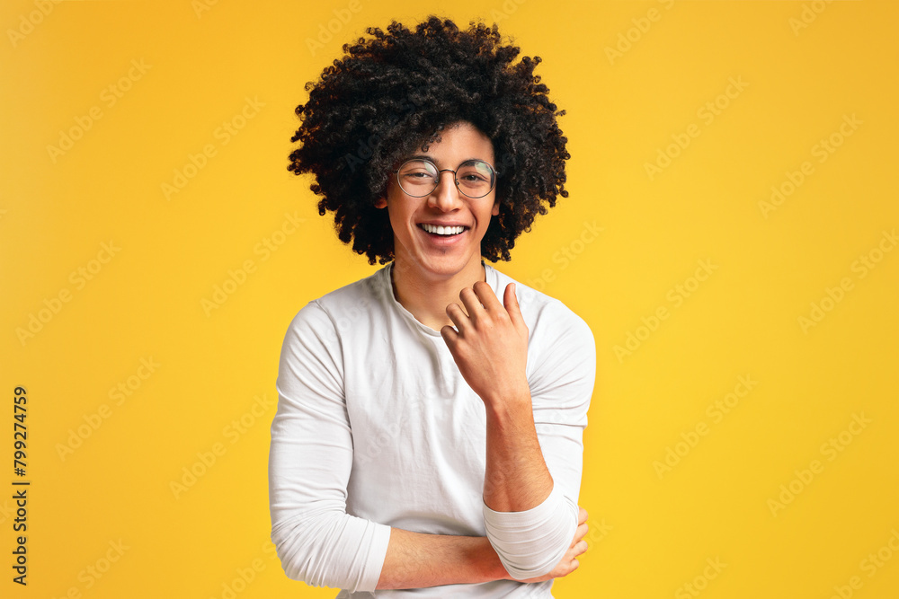 Cute carefree black curly guy laughing on orange background Cute carefree black curly guy laughing on orange background