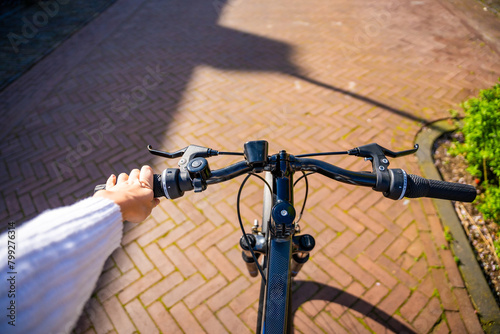 Cyclist woman riding in a sunny summer park, first-person view