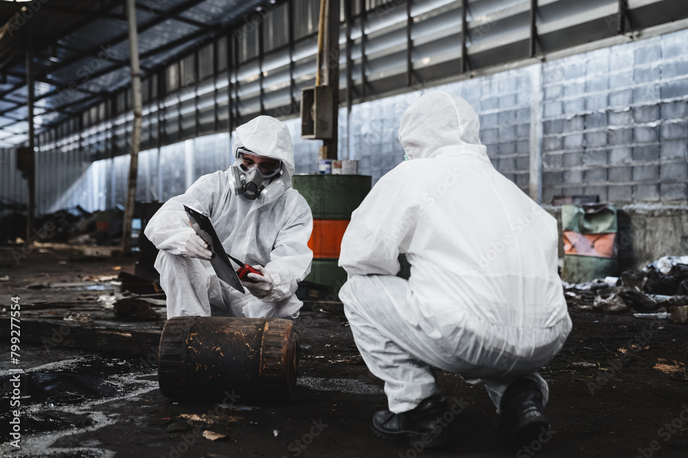 Workers in protective suits inspect chemicals in an old factory, safeguarding against hazards and contamination. This is part of an emergency response to a radioactive accident. Workers in protective suits inspect chemicals in an old factory, safeguarding against hazards and contamination. This is part of an emergency response to a radioactive accident.