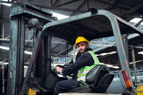 A man in a yellow helmet is driving a forklift in a warehouse