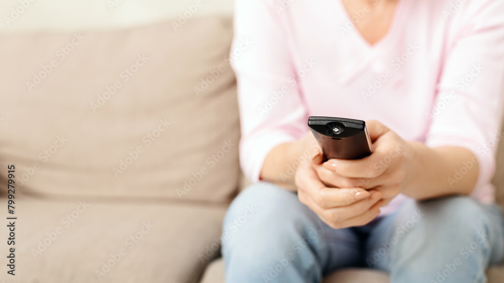 Lady Sitting on a Beige Couch Holding a Remote Control Lady Sitting on a Beige Couch Holding a Remote Control