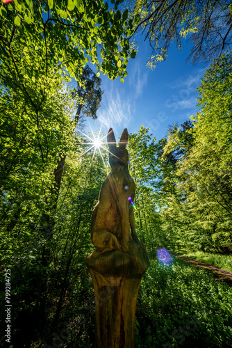 A Bunny sculpture in the forest with sunlight filtering through trees © AdobeTim82