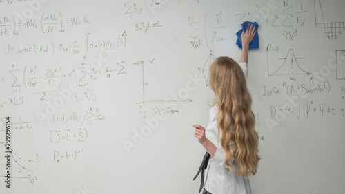 Caucasian woman erasing formulas from white board. 