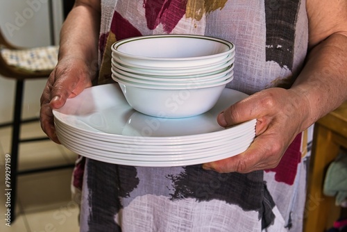 A stack of white clean plates in female hands.