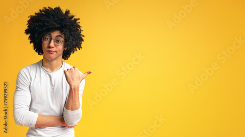Skeptical african man pointing aside at empty space photo
