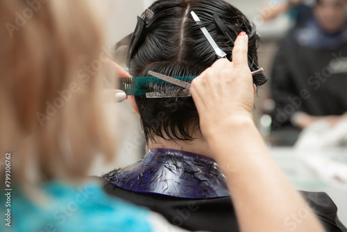 Hairdresser cuts dark short hair with scissors and comb