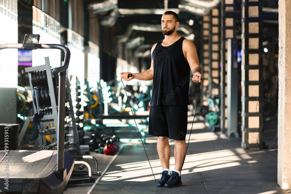 Handsome Millennial Man Holding Skipping Rope in Gym Handsome Millennial Man Holding Skipping Rope in Gym