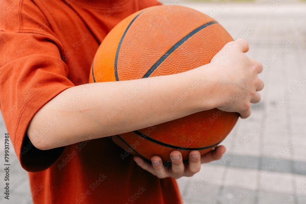 Fototapeta premium teenage boy wrapped his hands around the ball after playing basketball